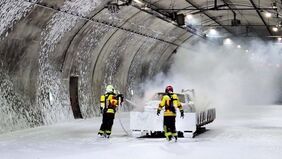 Feuerwehrleute löschen in einem Tunnel ein Fahrzeug.