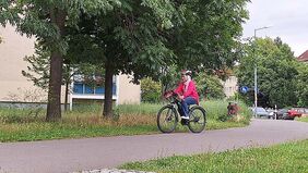 Eine Frau fährt Fahrrad auf einem Weg.